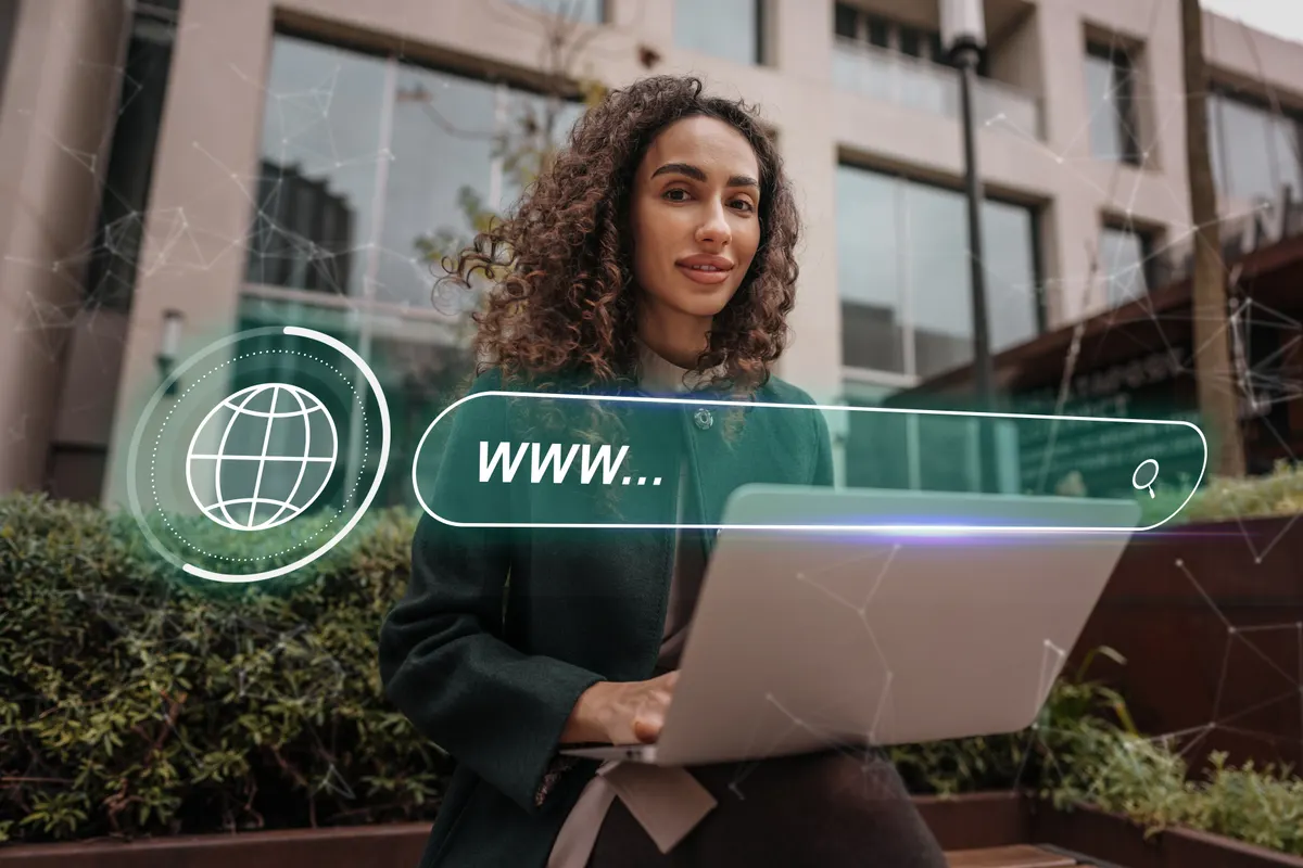 Jeune dirigeante avec un ordinateur portable devant une barre de recherche « www... » et un globe, illustration du choix d'un nom de domaine
